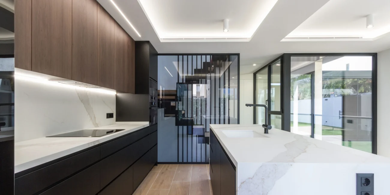 Cocina de lujo con isla de mármol y mobiliario minimalista en el proyecto residencial de Almadraba, construcción exclusiva de OCN en Castellón.