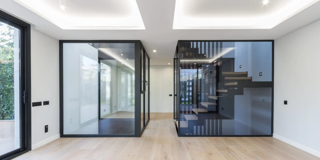 Interiorismo de lujo con cerramientos de cristal y escalera de diseño en la construcción residencial Almadraba exclusiva de OCN, empresa constructora, en Castellón