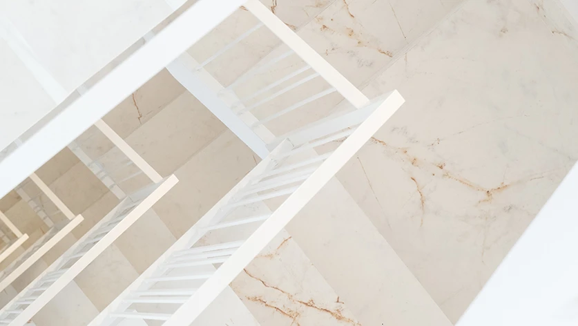 Escalera de diseño minimalista con peldaños de mármol veteado, un ejemplo de proyectos de construcción de lujo de nuestra empresa constructora en Castellón.