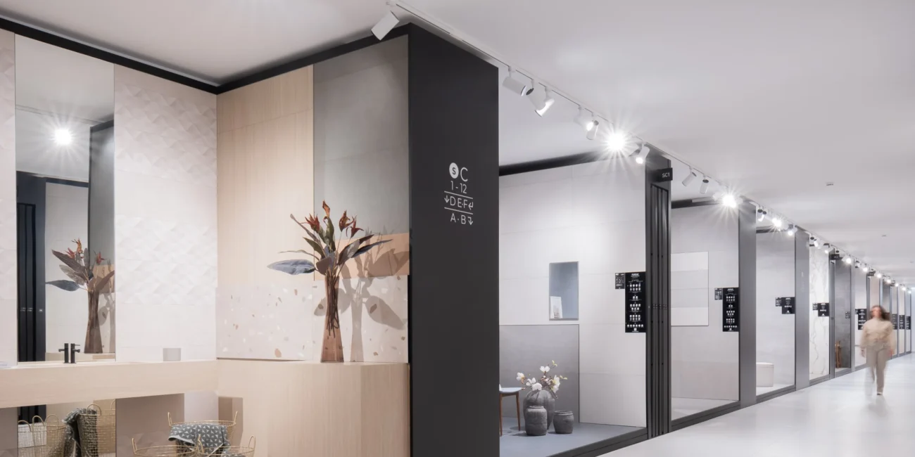 Sala de muestras cerámicas con diferentes acabados y texturas, destacando la combinación de azulejos decorativos y pavimentos de gran formato para proyectos de arquitectura iluminados por focos led de carril.
