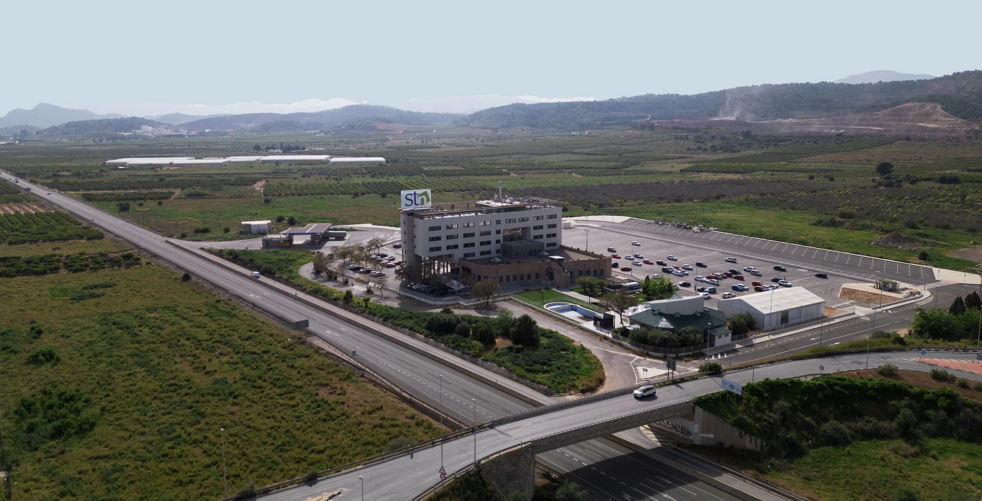 Vista aérea del complejo corporativo de STN Cerámica en Castellón, mostrando el edificio principal, parking y accesos desde la autovía en un entorno industrial.