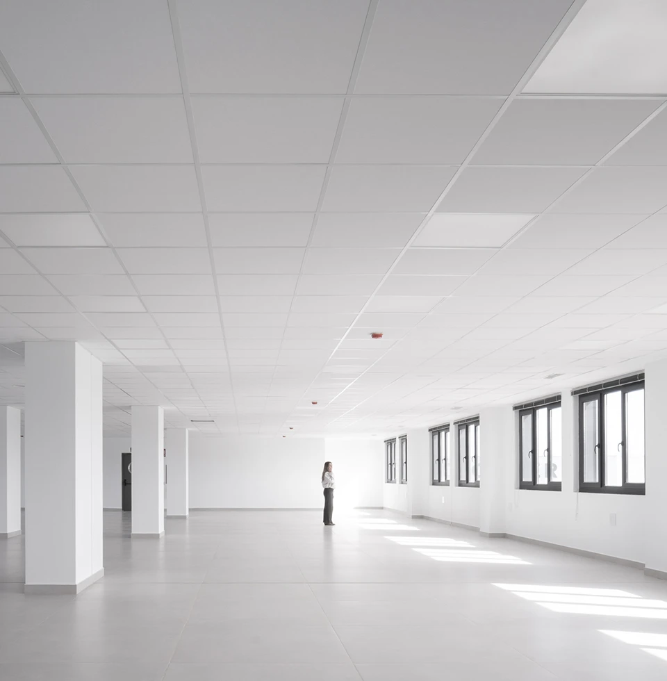 Planta de oficinas diáfana en edificio corporativo de STN Cerámica, con pavimentos cerámicos de gran formato, falso techo modular y pilares de hormigón integrados.
